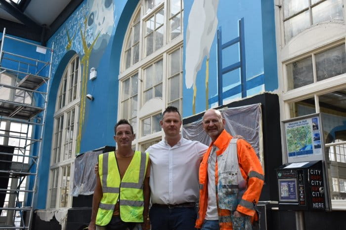 Three men standing in front of the Hull mural