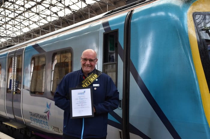 A TPE member of staff stood next to a train holding a certificate