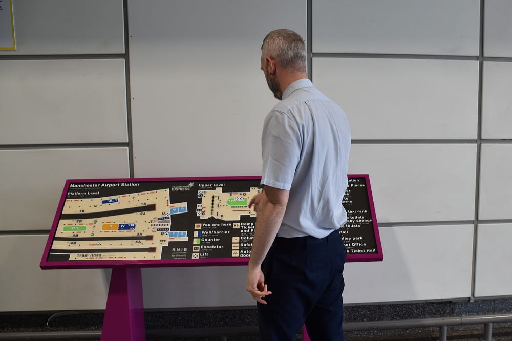 A man stood next to a tactile map using it