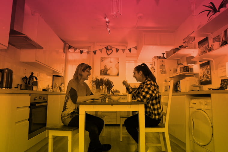 Teenage girl talking to a woman sat at a kitchen table