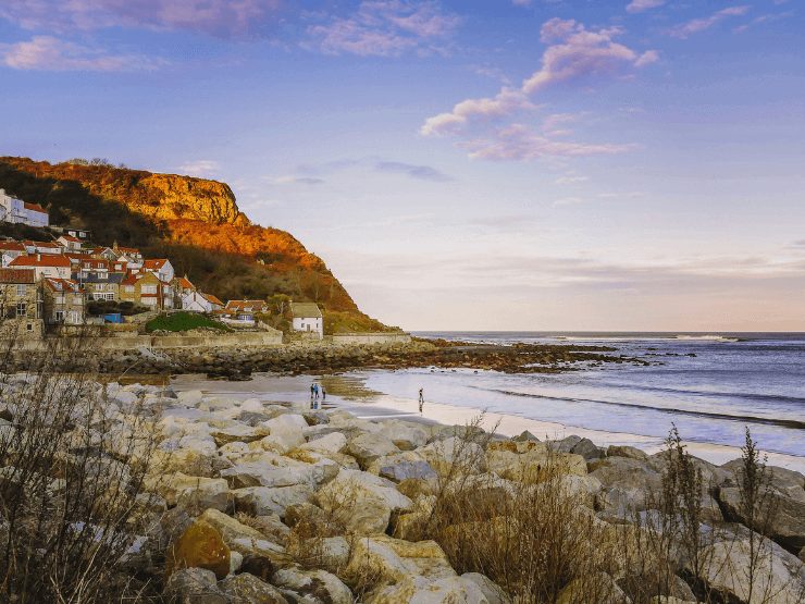 Runswick Bay at dusk with some buildings visible on a cliff by the sea