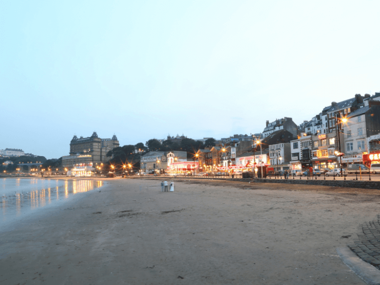 Scarborough beach in the evening with coastal shops and cafes visible