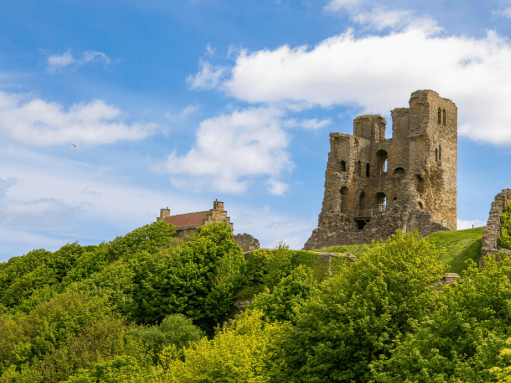 Scarborough castle ruins on a green hill in the day time