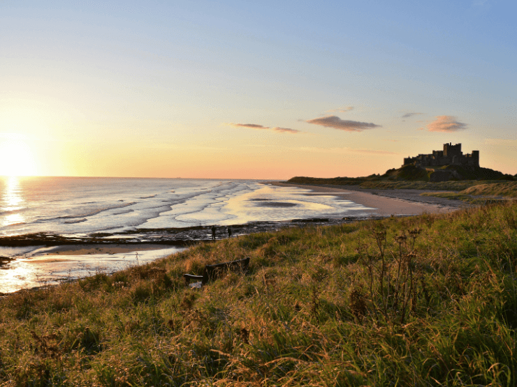 A coast at sunset in Northumberland, a castle can be seen in the background