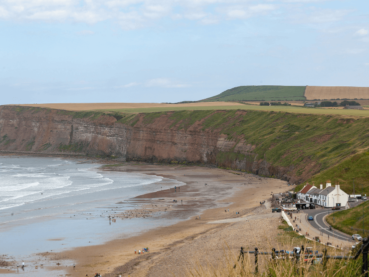 Saltburn beach in the day with a cliff backdrop