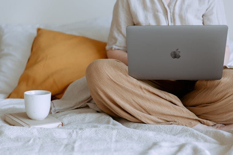 Person on apple laptop with mug and book
