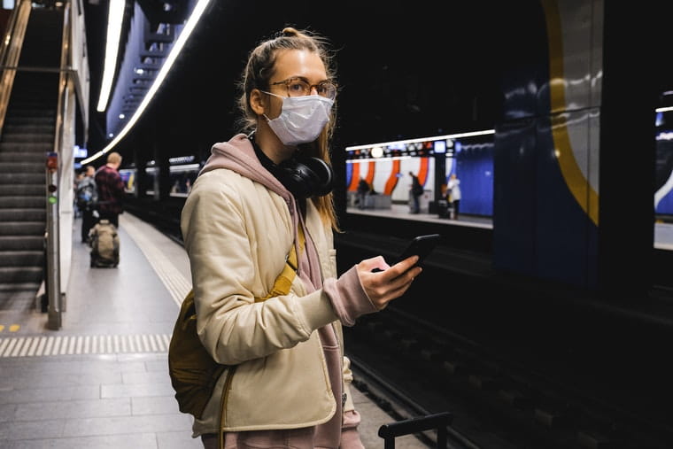 Woman wearing a face mask on a train station platform